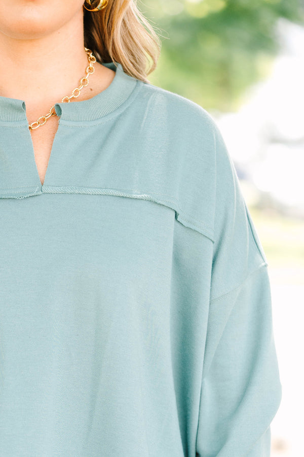 Plus size green tunic sweatshirt with a split v-neck, raw seam details, and a relaxed fit.