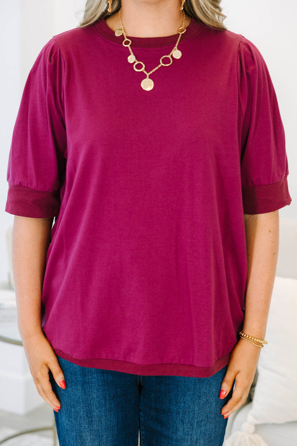 Plus Size burgundy short sleeve top with puffed shoulders and a round neckline.