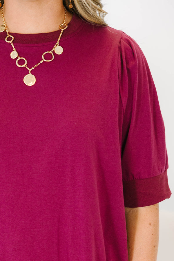Plus Size burgundy short sleeve top with puffed shoulders and a round neckline.