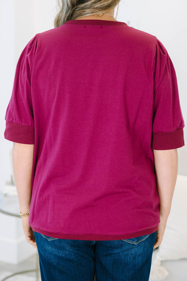 Plus Size burgundy short sleeve top with puffed shoulders and a round neckline.