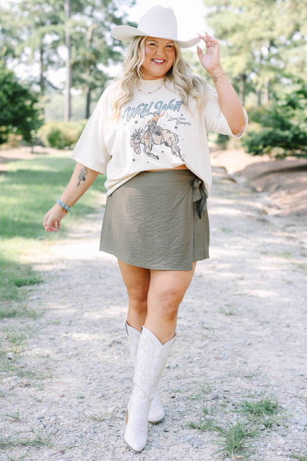 Plus Size olive green wrap-style skort with a side tie, paired with white embroidered cowboy boots.