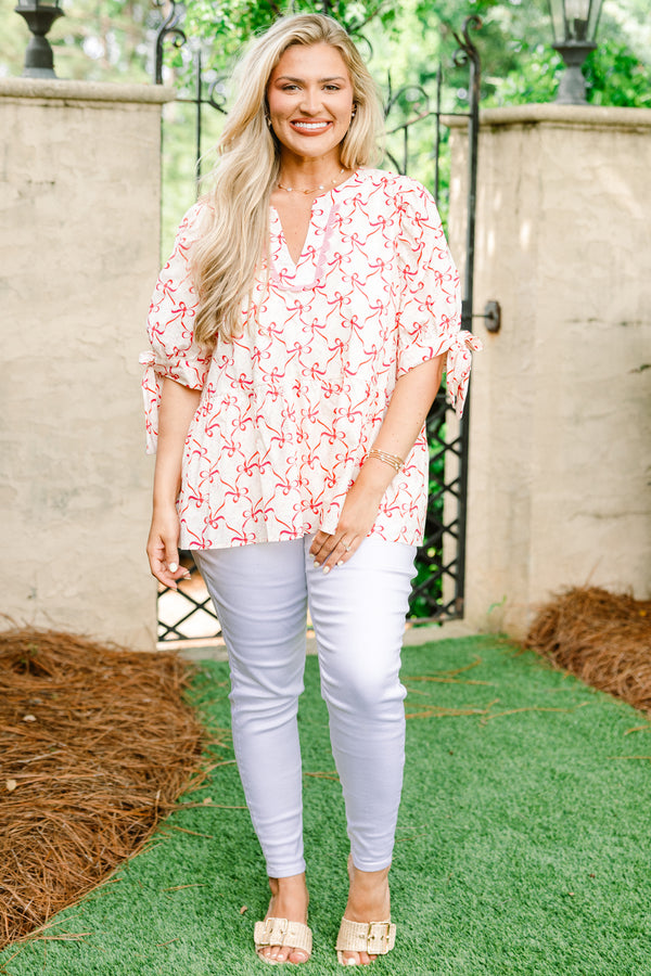 Plus Size white v-neck babydoll top with a pink bow print, ric rac trim, and tie-detail sleeves.