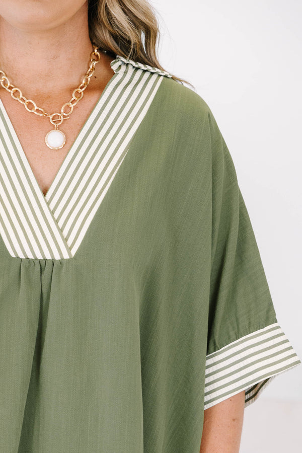 Plus size olive green flowy top with a striped V-neckline and matching striped sleeve cuffs.