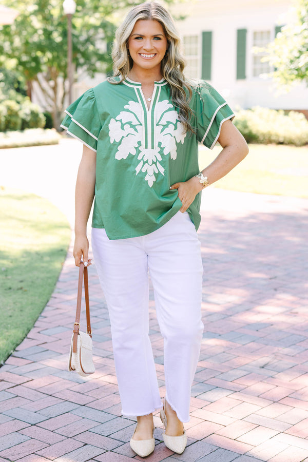 Plus size sage green top with white floral appliqué, ruffle sleeves, and a flowy silhouette.