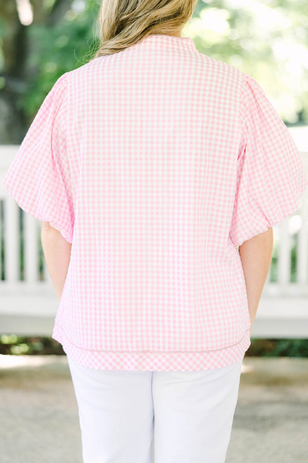 Plus size pink gingham top with puff sleeves and a v-neckline.