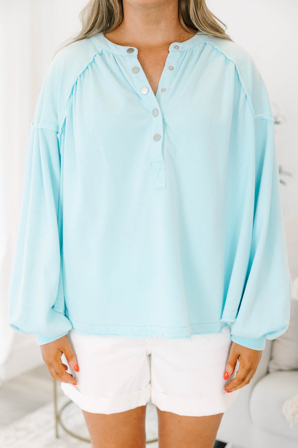 Plus size light blue pullover with a flowy fit, button-up neckline, and long sleeves.