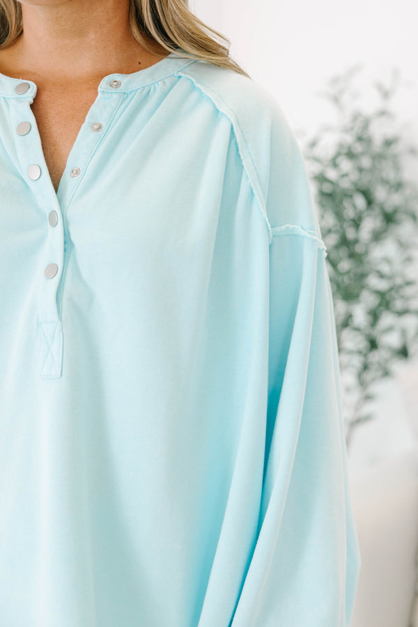 Plus size light blue pullover with a flowy fit, button-up neckline, and long sleeves.