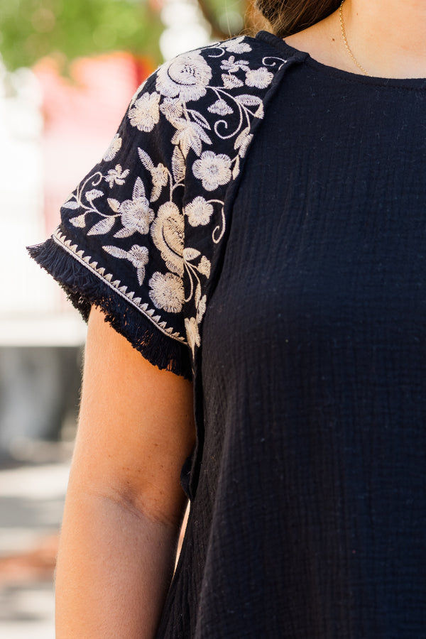 Chic Soul plus size clothing, black linen short sleeve top with round neckline and white embroidery along sleeves with raw hem detail
