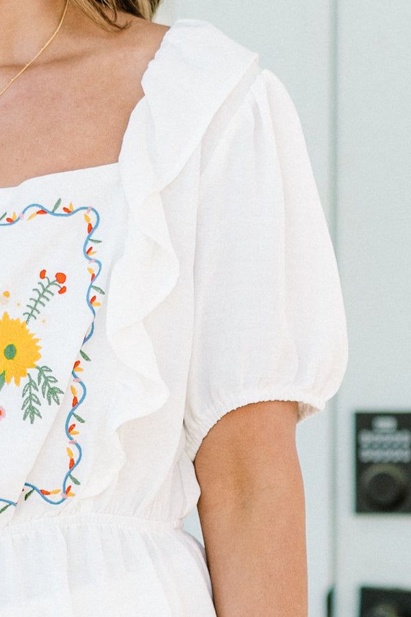 Plus Size white babydoll top with ruffled square neckline and colorful floral embroidery.