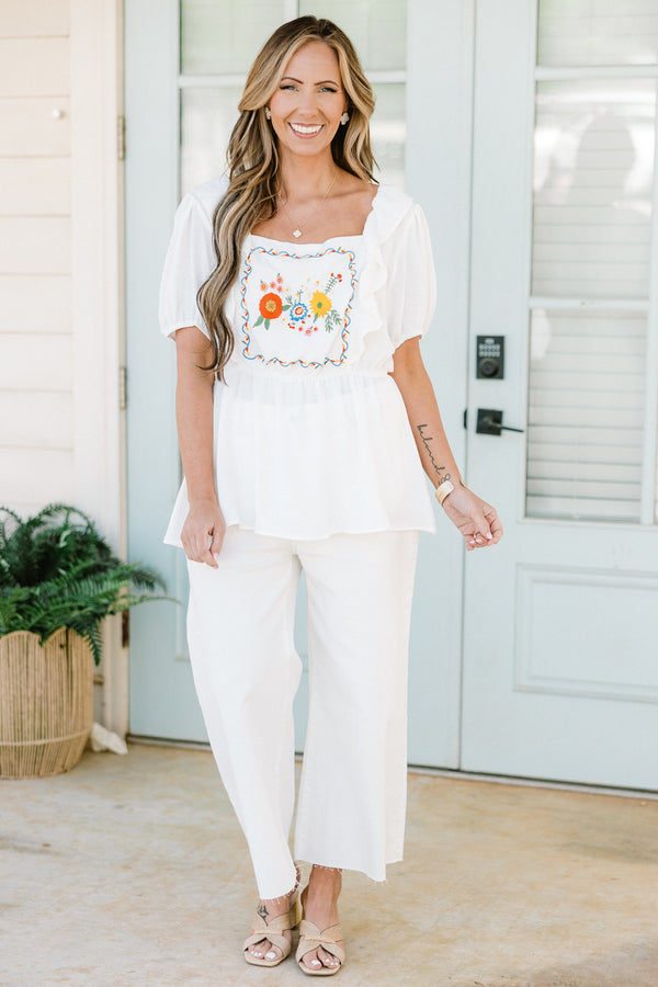 Plus Size white babydoll top with ruffled square neckline and colorful floral embroidery.