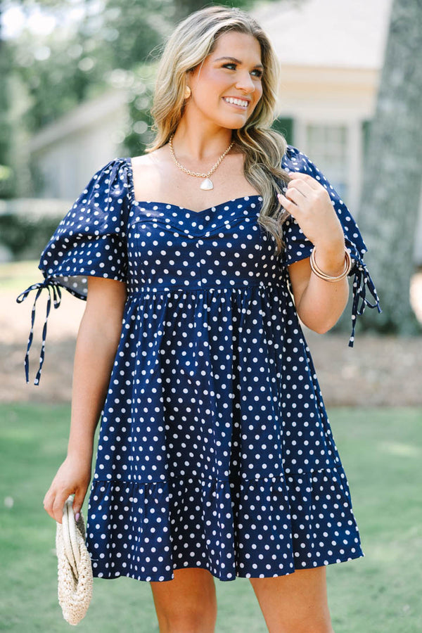 Plus Size navy blue polka dot cotton dress with puff sleeves, tie details, and a tiered skirt.