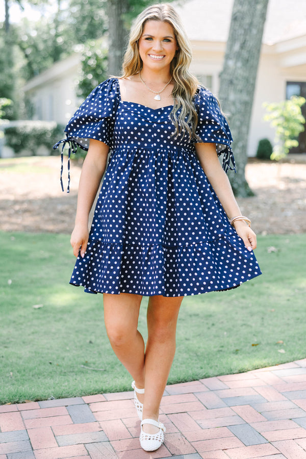 Plus Size navy blue polka dot cotton dress with puff sleeves, tie details, and a tiered skirt.