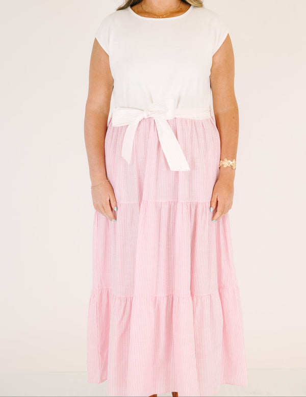 Plus Size maxi dress with a white short-sleeve bodice and a tiered pink striped skirt with a bow.