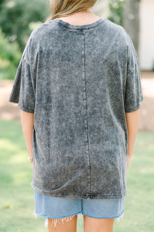 Plus size woman in a black acid wash relaxed tee with a floral graphic and light wash denim shorts.