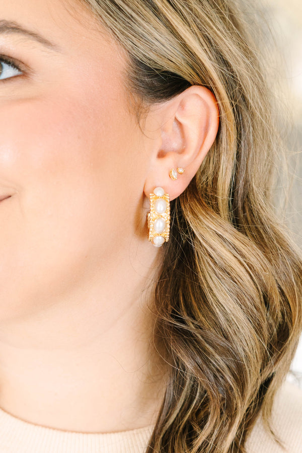 Close-up of a model wearing gold Honey Glow hoop earrings with white pearl accents.