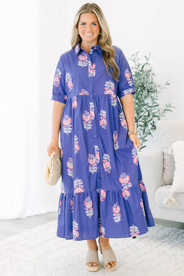 Plus size blue floral maxi dress with a flowy tiered skirt, button-down front, and short sleeves.
