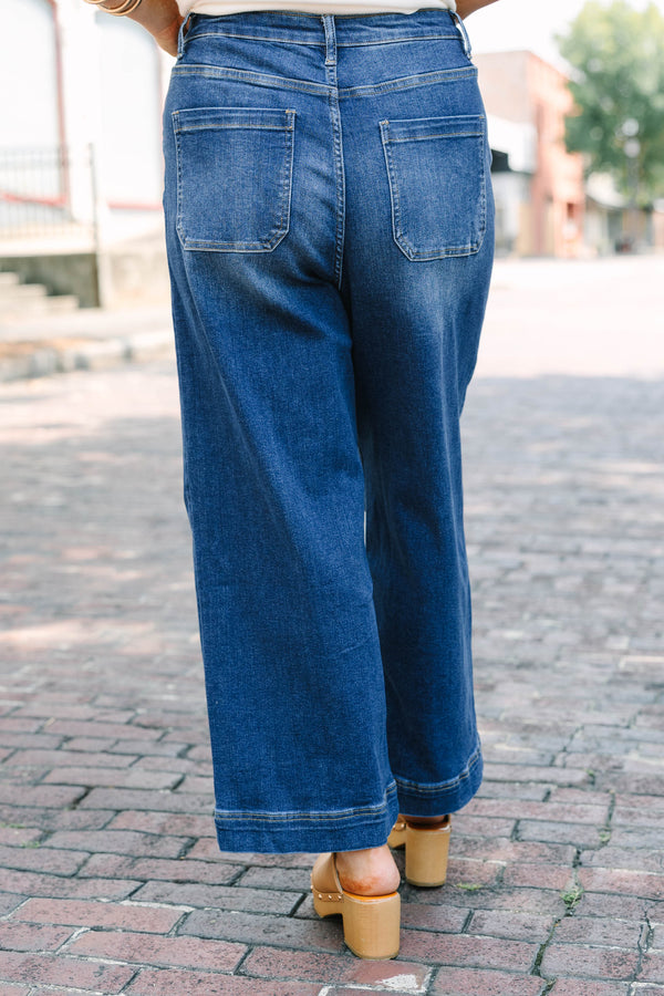 Plus Size high-rise, wide-leg dark wash jeans with front pintuck seams and a wide hem.