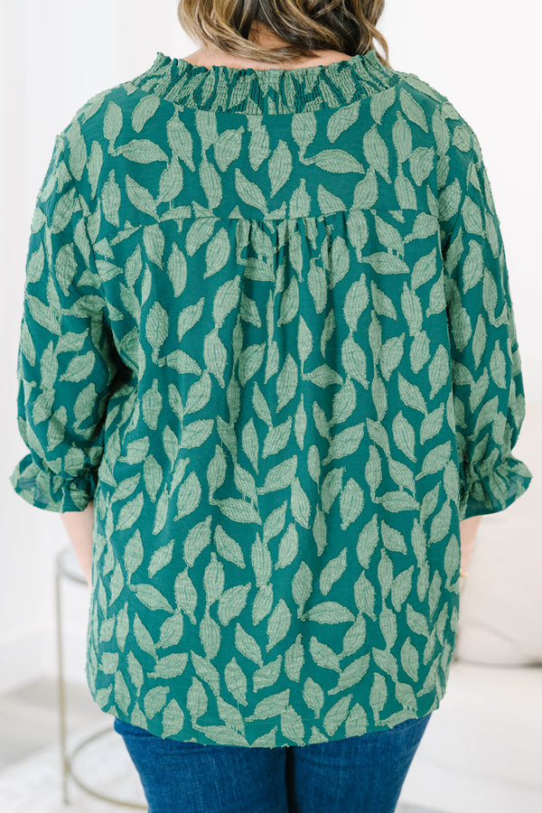 Plus size woman in a green leaf print top with a flowy fit, V-neckline, and ruffled sleeves.
