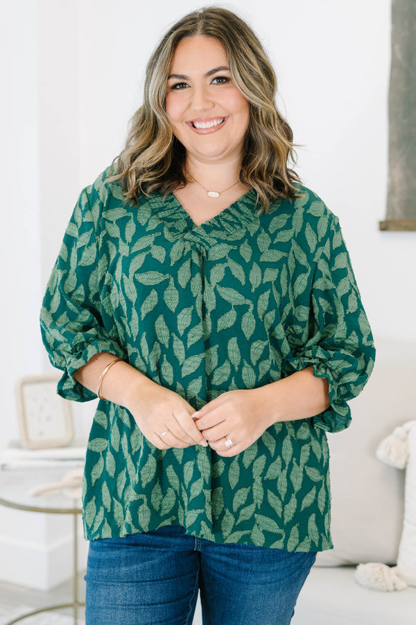 Plus size woman in a green leaf print top with a flowy fit, V-neckline, and ruffled sleeves.