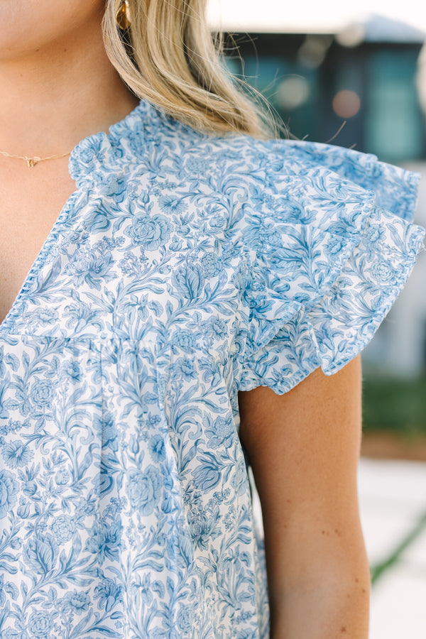 Chic Soul plus size clothing, light blue top with flutter sleeves a slight v-neckline as well a a ruffle detail on the neckline and a floral pattern throughout