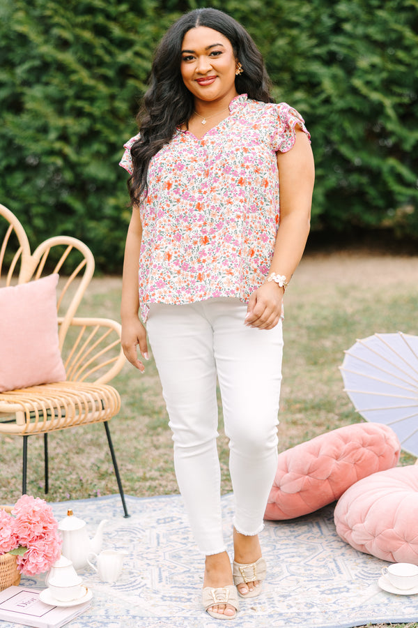 Chic Soul plus size clothing, pink top with a multi-color floral pattern throughout and fluttersleeeves with a slight v-neckline and ruffle details going along the collar of the top 
