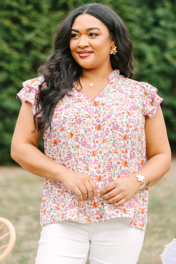 Chic Soul plus size clothing, pink top with a multi-color floral pattern throughout and fluttersleeeves with a slight v-neckline and ruffle details going along the collar of the top 
