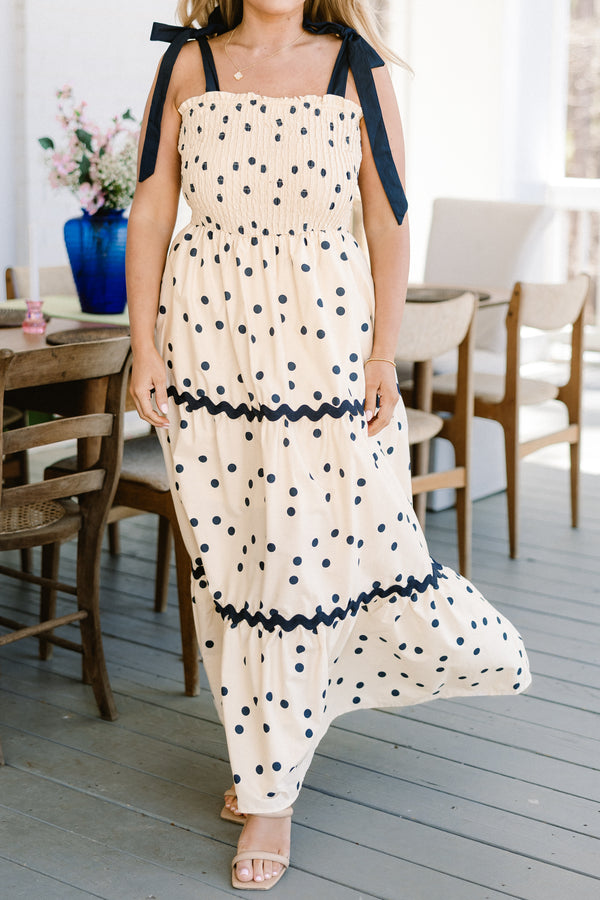 Chic Soul plus size clothing, ecru cream ruffled maxi dress with a square-neckline with black bow ties on the shoulders and a smocked bodice with a ric rac black lining and a black polka dotted pattern 