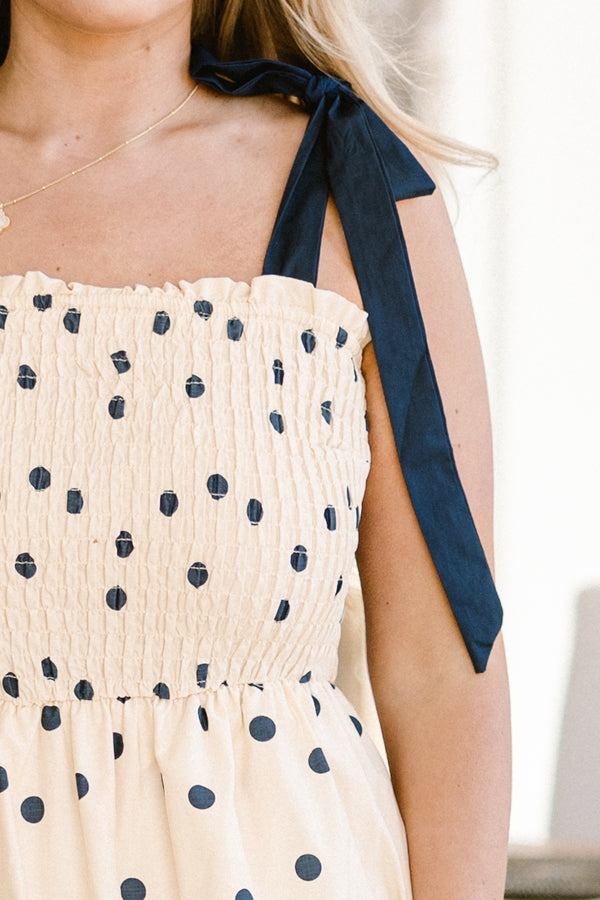 Chic Soul plus size clothing, ecru cream ruffled maxi dress with a square-neckline with black bow ties on the shoulders and a smocked bodice with a ric rac black lining and a black polka dotted pattern 