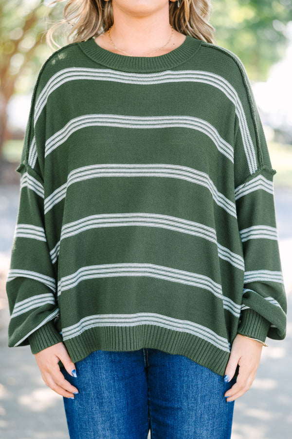 Plus size woman in an olive green oversized striped sweater with a relaxed, flowy fit.