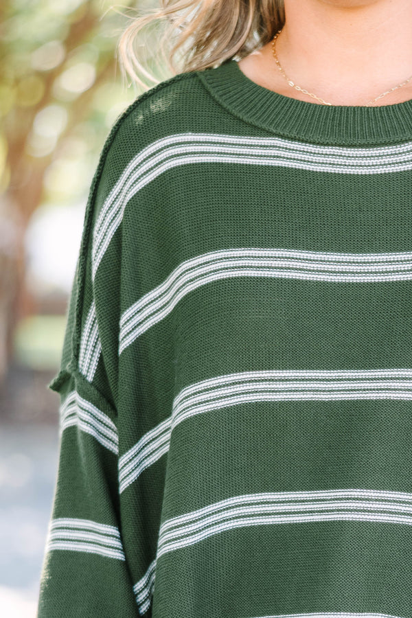 Plus size woman in an olive green oversized striped sweater with a relaxed, flowy fit.