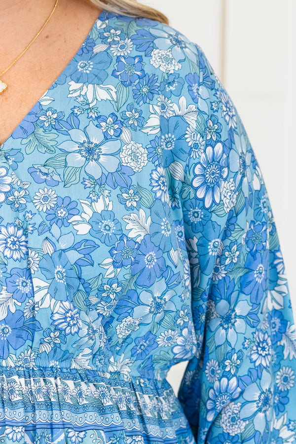 Chic Soul plus size clothing, long-sleeve blue baby doll top with a v-neckline and smocked detailing with a tie on the waist with a darker blue floral pattern 