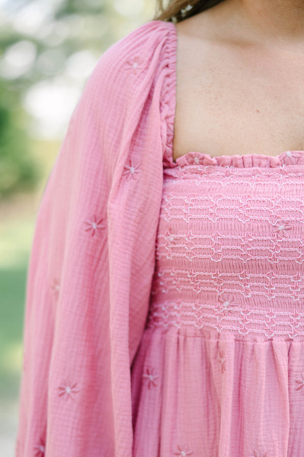 Plus size pink cotton dress with smocked bodice, long puff sleeves, and floral embroidery.