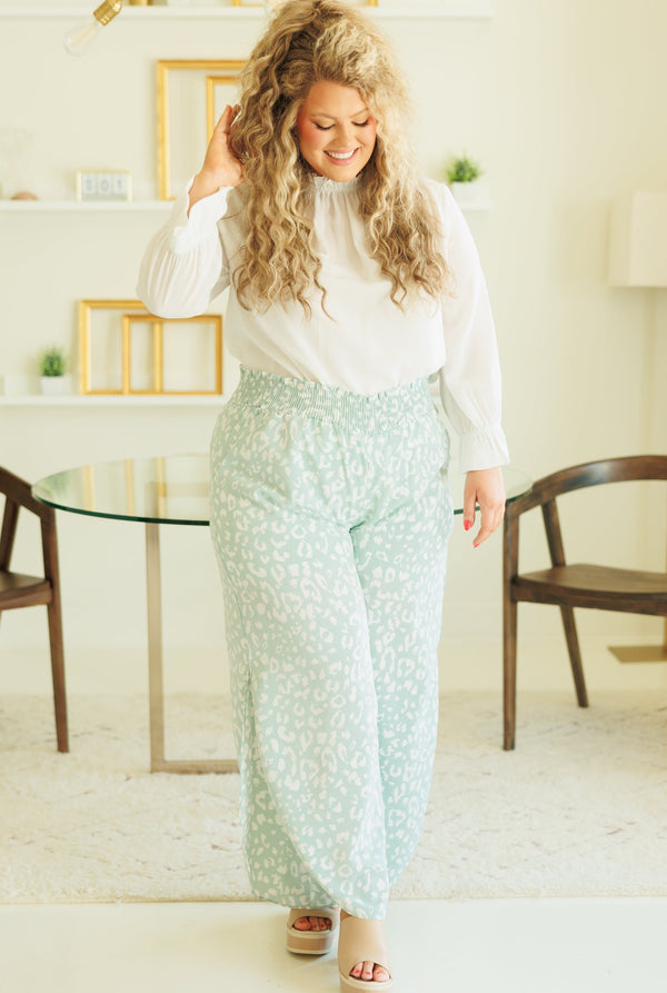 Plus Size white high-neck top with ruffled collar and cuffs paired with mint leopard print pants.