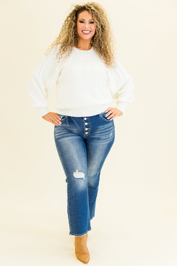 mid-waisted subtle flare cropped dark wash denim jeans with slight distressed detailing along knees and multiple silver buttons on waistline 
