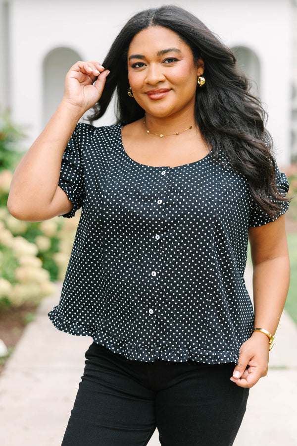 Short-sleeve black and white polka-dot blouse featuring a scoop neckline, front button closure, and a playful ruffled hem