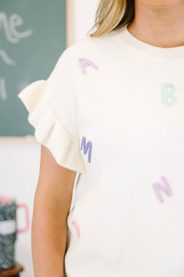 Plus size cream knit top with ruffle flutter sleeves and colorful embroidered alphabet letters.