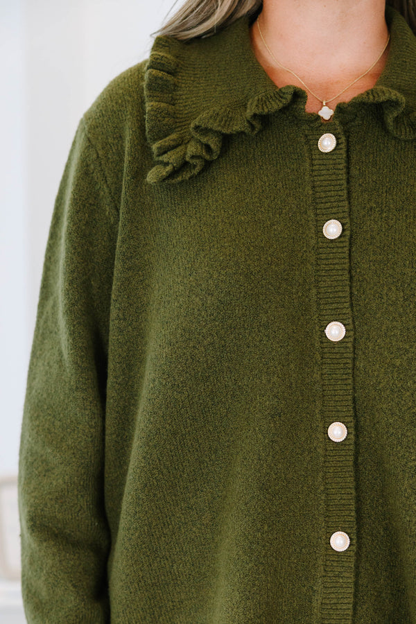 Plus size olive green cardigan with a ruffled collar, pearl buttons, and a flowy, relaxed fit.