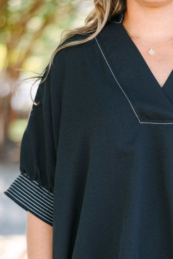 Plus Size black v-neck top with white contrast stitching on the neckline, cuffs, and hem.