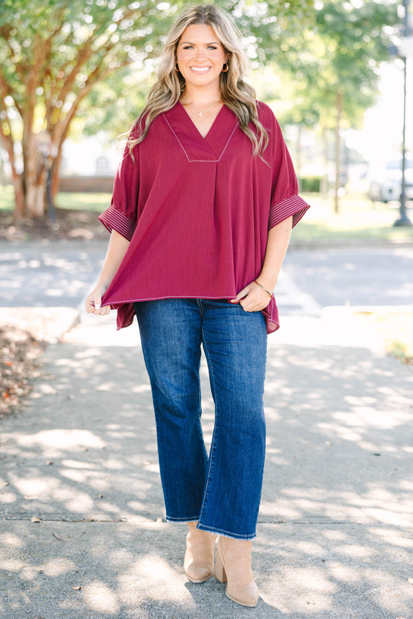 Plus size burgundy top with a flowy fit, V-neck, and striped sleeve details.