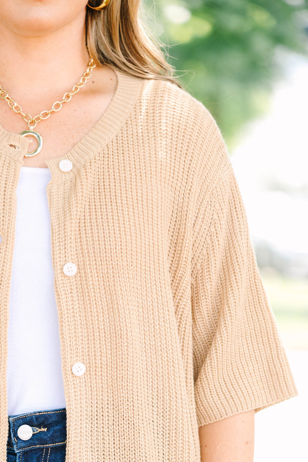 Plus size woman in a tan, short-sleeve knit cardigan with a flowy fit and button-down front.