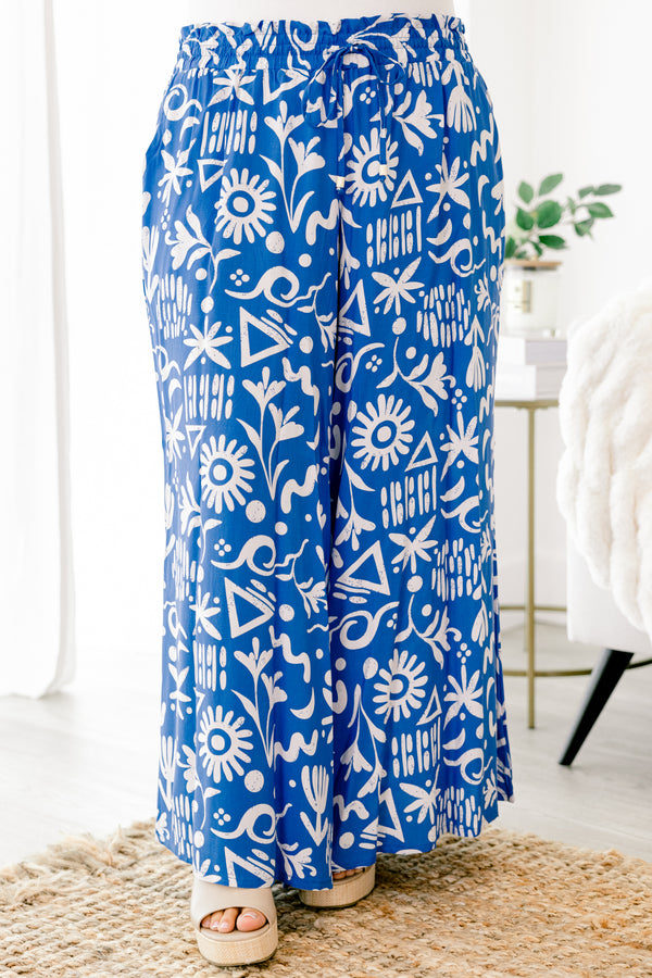 Plus Size blue wide-leg pants with a white tropical print, elastic drawstring waist, and pockets.