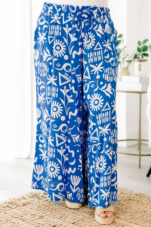 Plus Size blue wide-leg pants with a white tropical print, elastic drawstring waist, and pockets.
