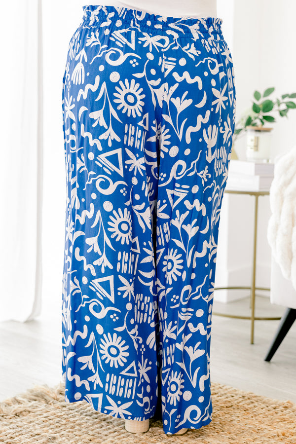 Plus Size blue wide-leg pants with a white tropical print, elastic drawstring waist, and pockets.