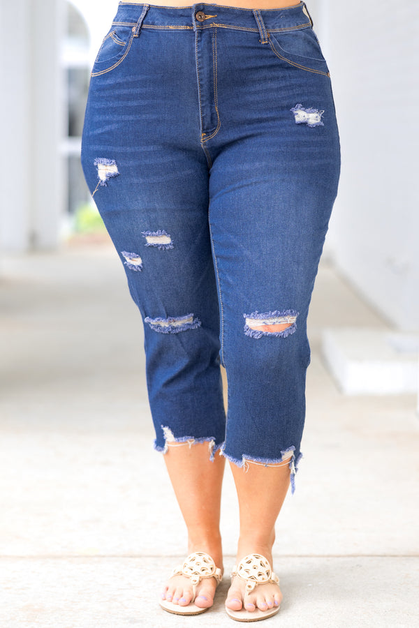 Plus Size medium wash denim capris with a distressed design and frayed hems.