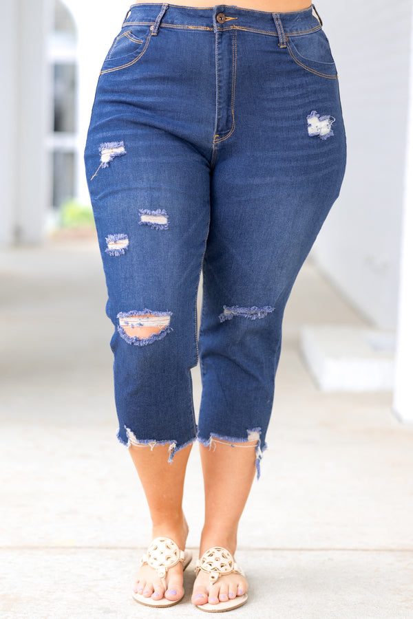 Plus Size medium wash denim capris with a distressed design and frayed hems.