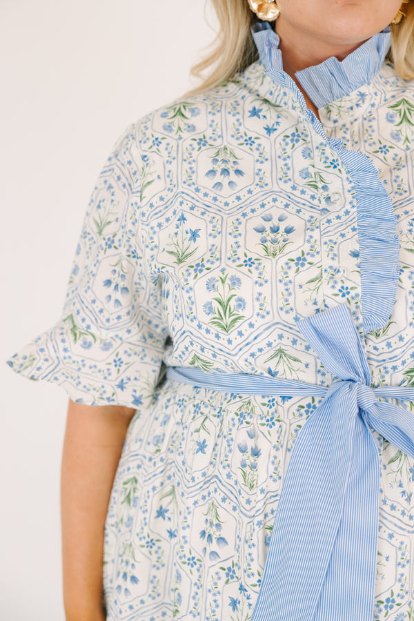 Chic Soul plus size clothing, blue maxi dress with shorts sleeves that flare out a blue multi floral pattern and a blue belt that ties into a bow that goes around the waist as blue ruffling details going along the neckline 