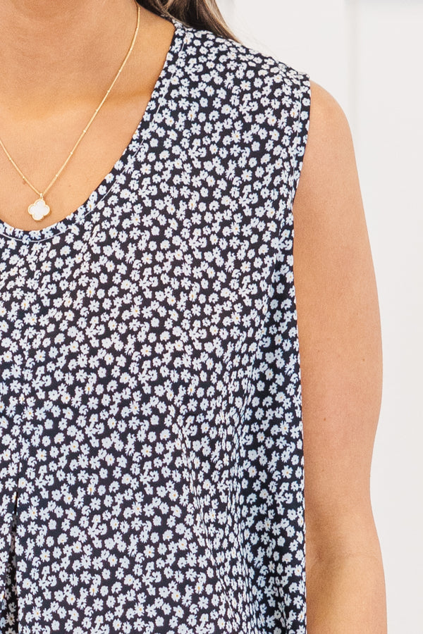 Plus Size black sleeveless top with a white floral pattern, V-neckline, and flowy pleated fit.