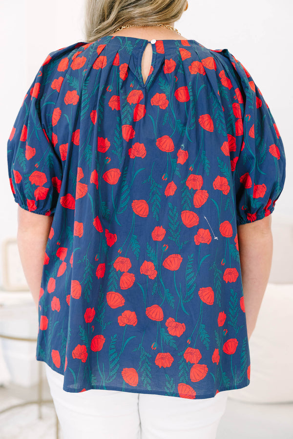 Plus size navy top with red poppy print, flowy fit, and puff sleeves.