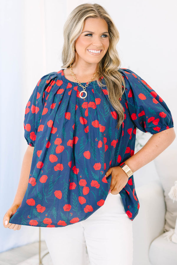 Plus size navy top with red poppy print, flowy fit, and puff sleeves.