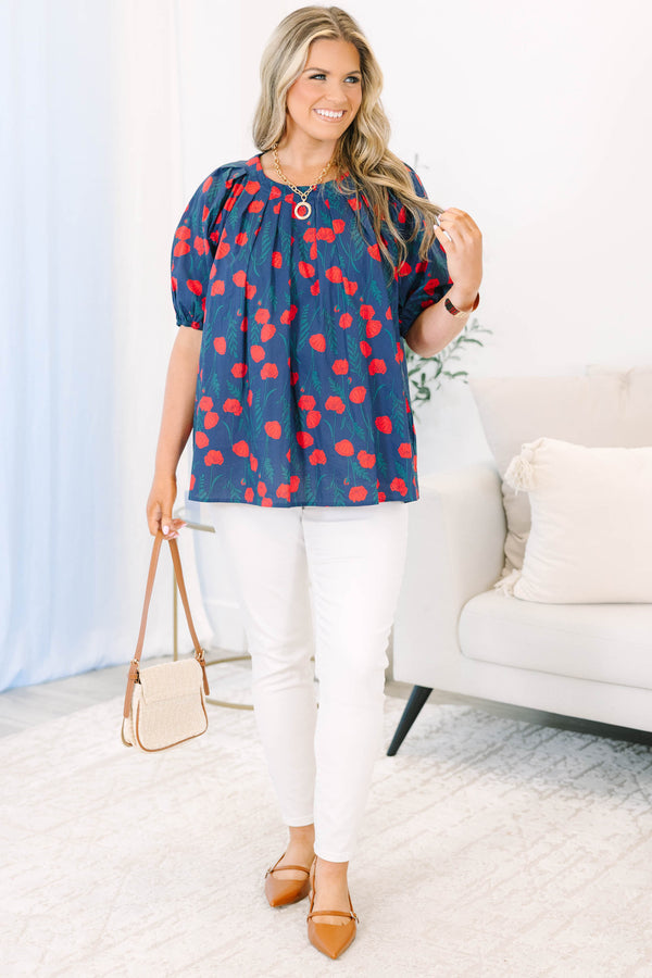 Plus size navy top with red poppy print, flowy fit, and puff sleeves.